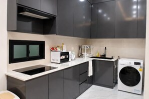Een moderne keuken met donkere kasten, een inbouwmagnetron en een voorlader wasmachine.