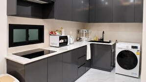 A modern kitchen with dark cabinets, a built-in microwave, a sink, and a front-loading washing machine. - Luxury 3BR Private Pool Villa Near Walking Street Pattaya (Pattaya)