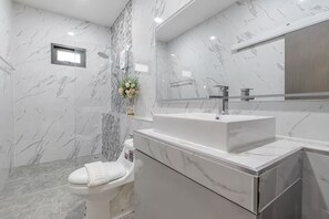 Un baño moderno con pared de mármol, inodoro, lavamanos y ducha.