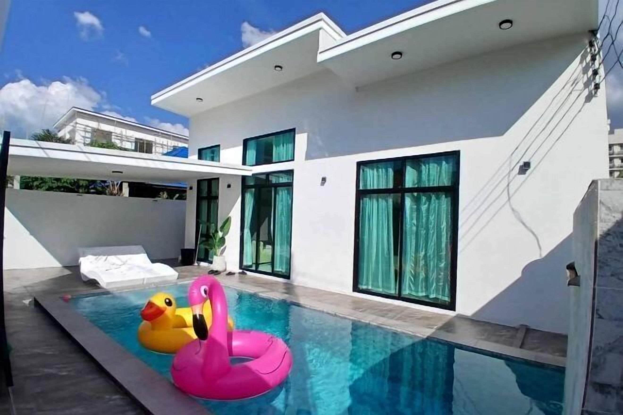 A modern house with a swimming pool, a white exterior, and large windows.