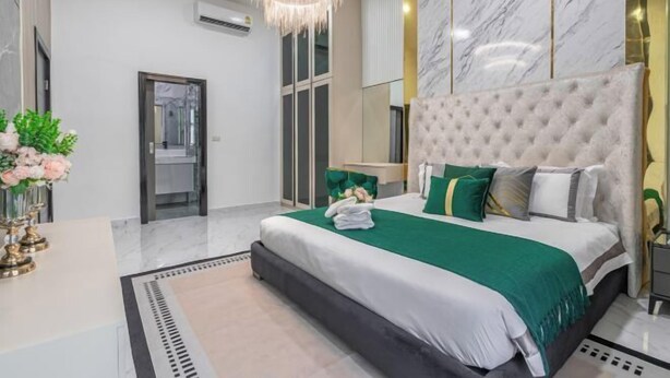 A modern bedroom with a large bed, a chandelier, and marble walls. - Luxury 3BR Private Pool Villa Near Walking Street Pattaya (Pattaya)