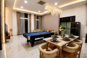 Una sala moderna con mesa de billar, comedor y sillas.