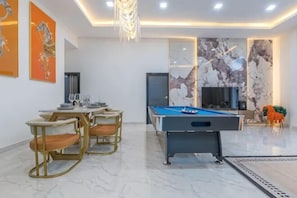 Una sala de estar moderna con mesa de billar, zona de estar y televisor.