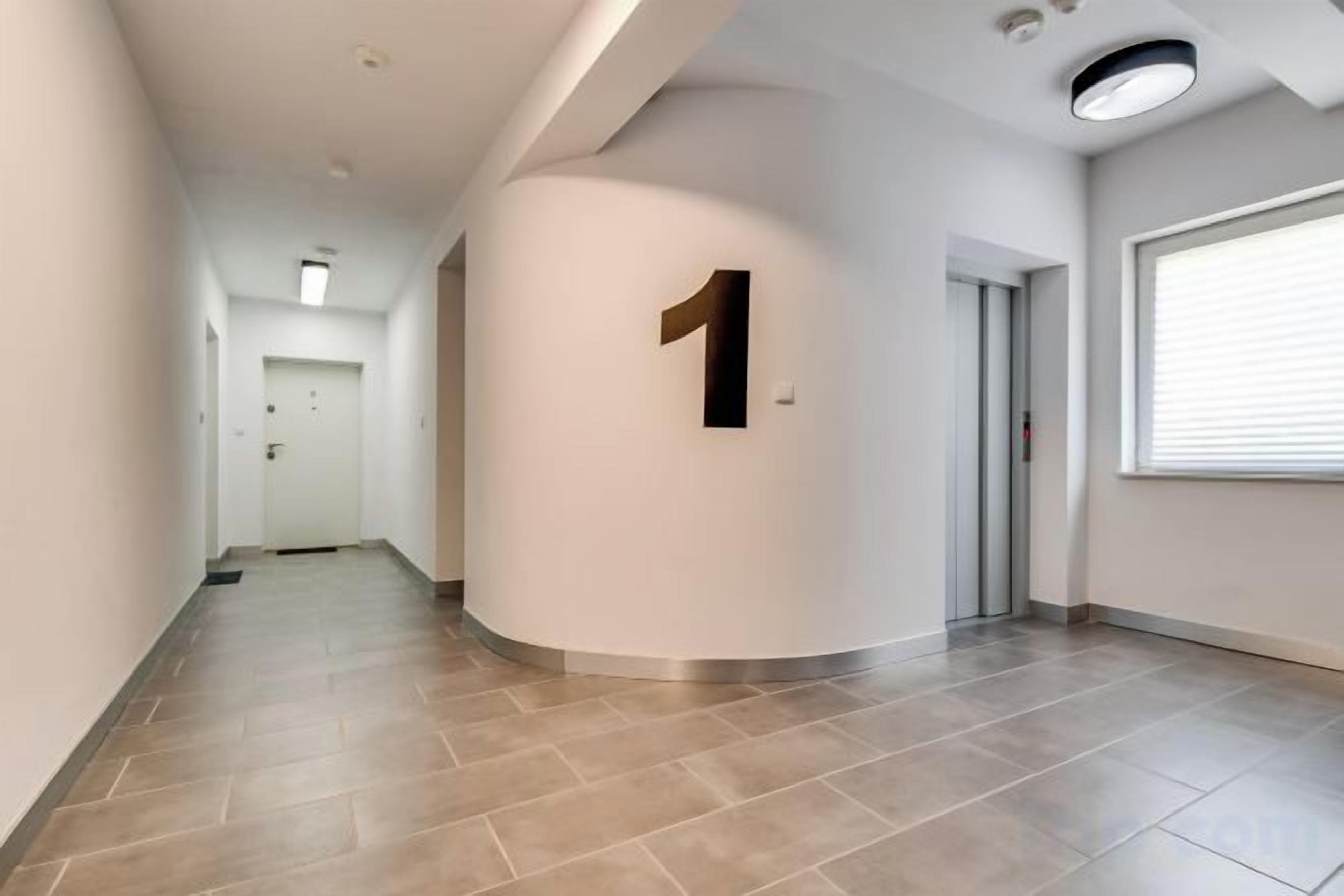 A hallway with a number 1 sign, a door, and a window with blinds.