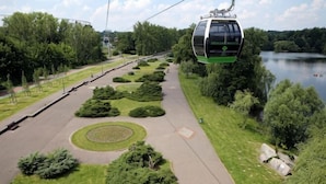 A cable car system, a paved walkway, and a landscaped area with trees and a lake. - GreenApartments (Chorzow)