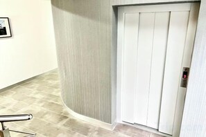 A white elevator door with a digital display showing the number 5. - GreenApartments (Chorzow)