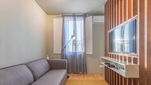 Een moderne woonkamer met een grijze bank, een wandgemonteerde televisie en een houten accentmuur.
