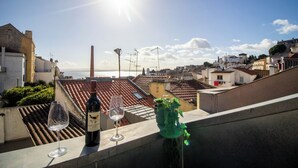 A rooftop terrace with a bottle of wine, a glass, and a potted plant.