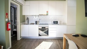 A modern kitchen with white cabinets, a built-in oven, a microwave, and a coffee maker.