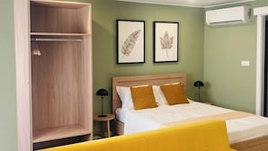 A bedroom with a bed, a yellow sofa, a wardrobe, and two framed leaves on the wall. - Loios Suites and Apartments (Lisbon)