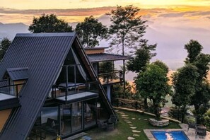 Un edificio moderno de varios pisos con grandes ventanales y una terraza en la azotea.