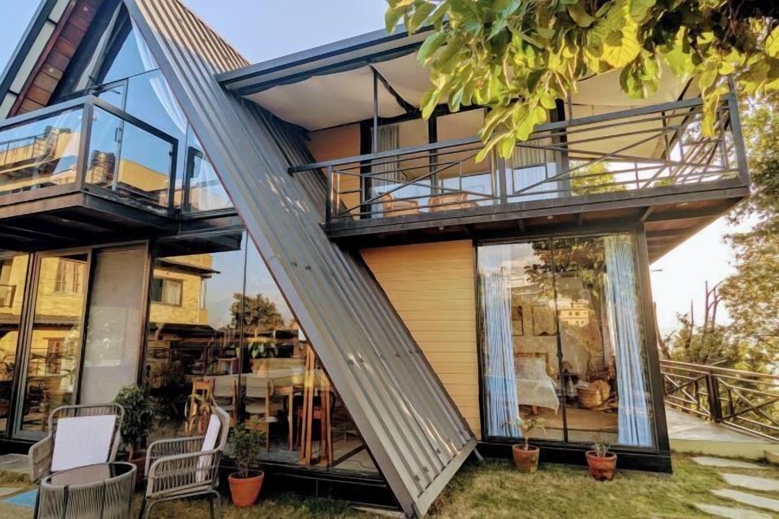 A modern building with a glass facade, a metal staircase, and outdoor seating.