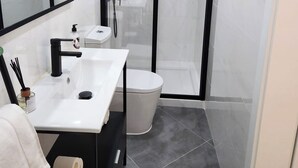 A modern bathroom with a white sink, black faucet, and a glass shower enclosure.