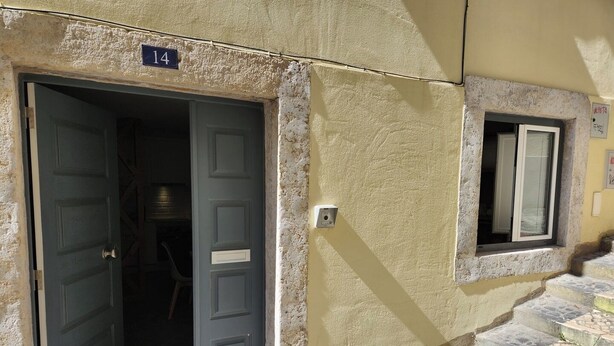 A building entrance with a door, a window, and a stone staircase.