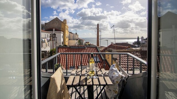 Un balcon avec une table, une bouteille et une chaise.