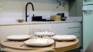 A modern kitchen with white cabinets, a black faucet, and a wooden table set for a meal. - Amazing Apartment @ Graça, Lisbon (Lisbon)