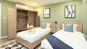 A bedroom with two beds, a wardrobe, a bedside table with a lamp, and a small table with a vase and cups. - Amazing Apartment @ Graça, Lisbon (Lisbon)