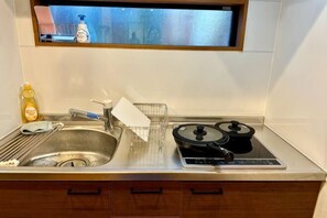 Una cocina con un lavamanos, estufa y ventana sobre el lavamanos.