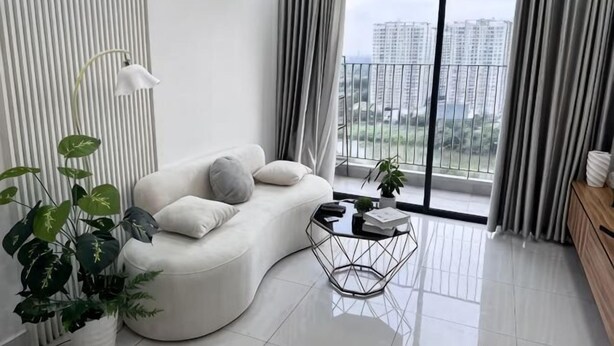 A modern living room with a curved sofa, a coffee table, and a view of a balcony.