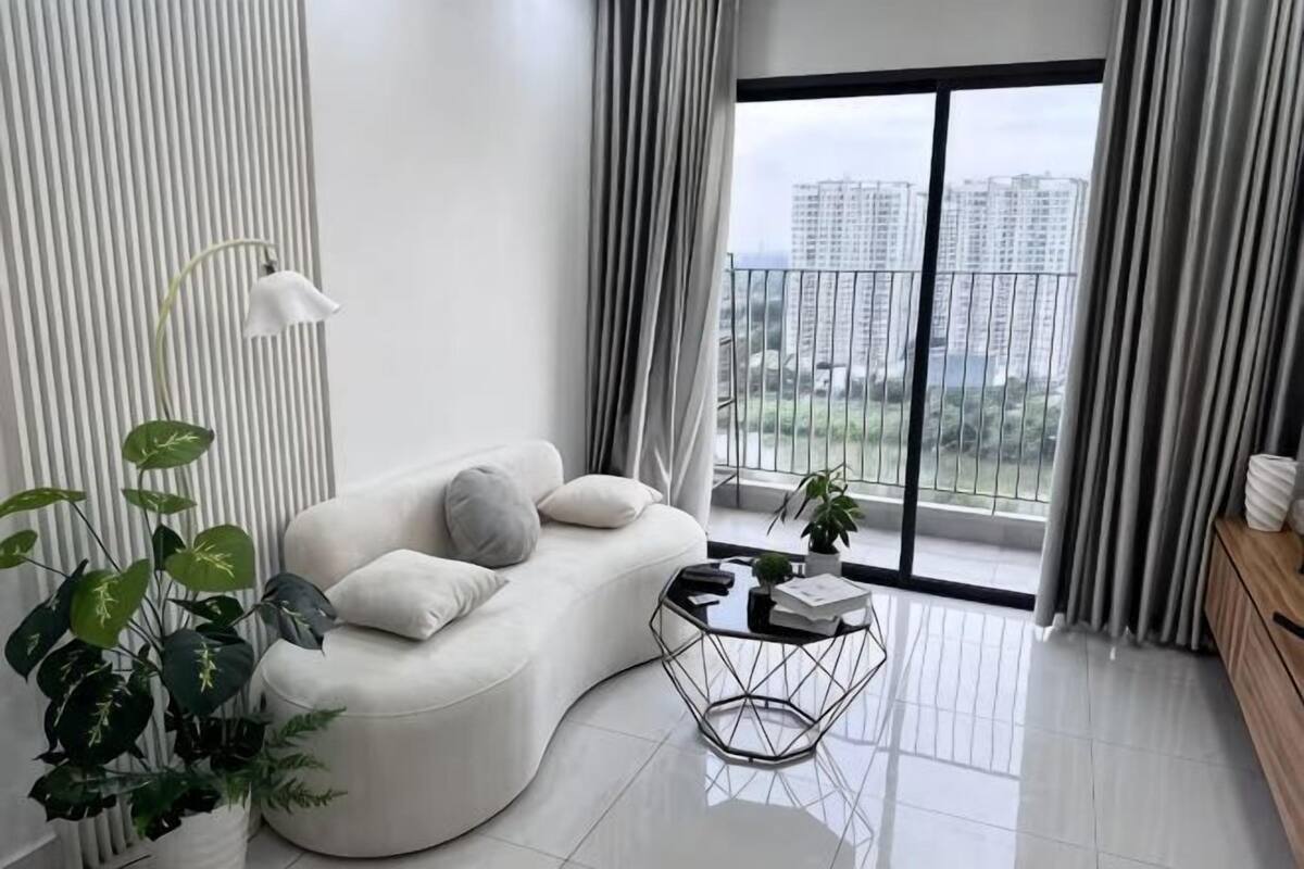 Un salon moderne avec un canapé aux lignes courbes, une table basse et une vue sur un balcon.