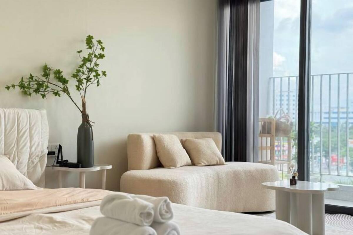 Une chambre d’hôtel avec un lit, un canapé, une petite table, un vase avec une plante et un balcon avec vue.