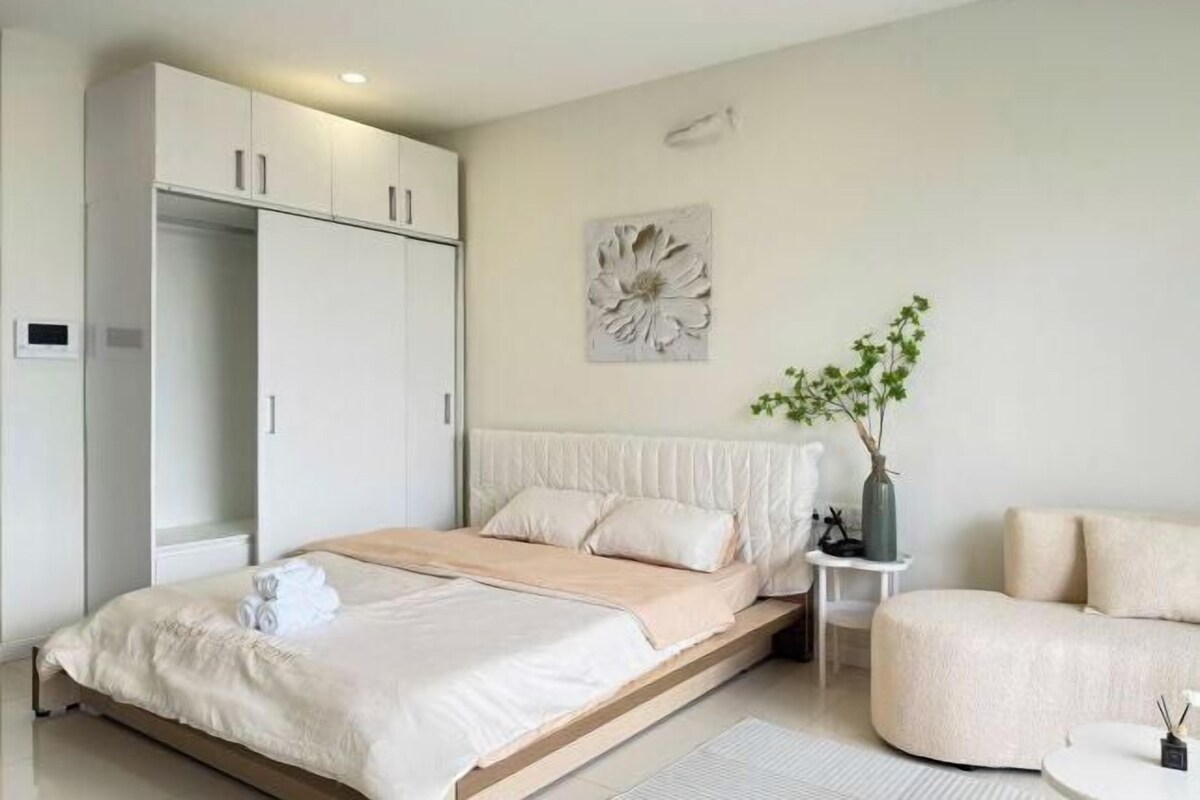 Une chambre à coucher avec un lit, une armoire, une petite table avec une plante et un canapé.