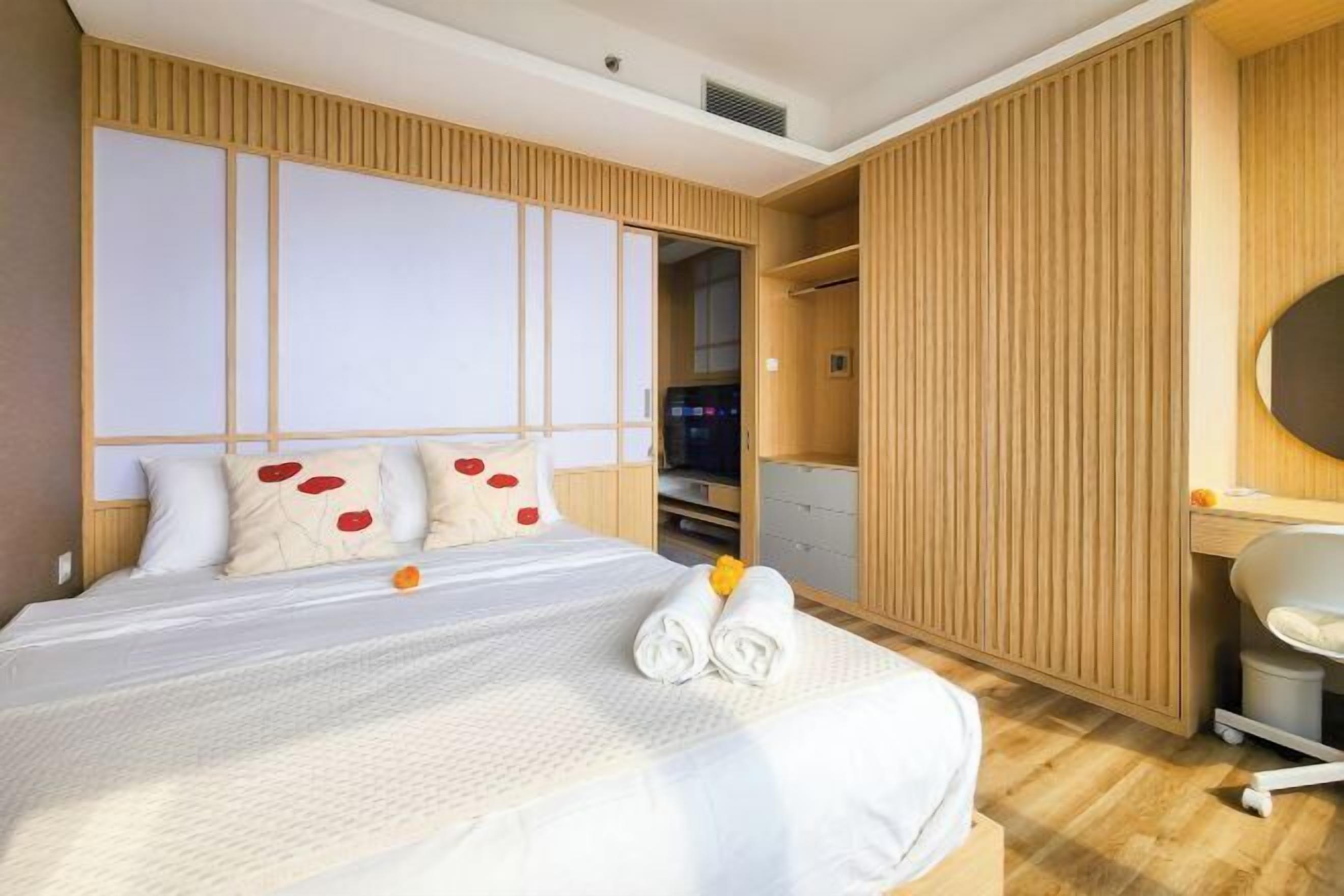 A hotel room with a bed, a wardrobe, a desk, and a chair.