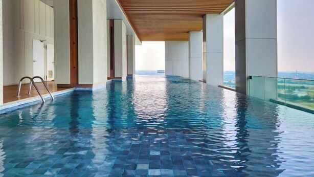 Une piscine intérieure moderne, avec une eau d’un bleu limpide, un plafond en bois et une vue sur le paysage.