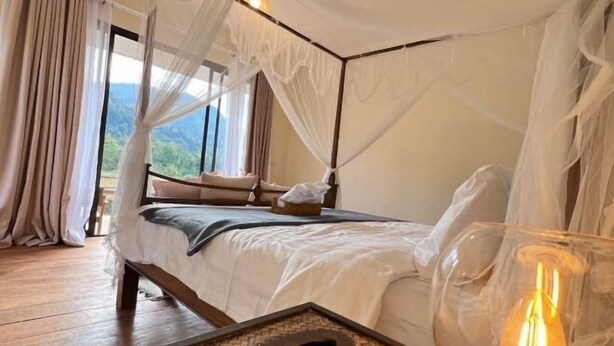 A bedroom with a canopy bed, wooden flooring, and a bedside table with a lamp. - Chan Rak Khao Villa (Bo Kluea)