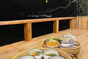 Una mesa de comedor con diversos platos y vista al agua.