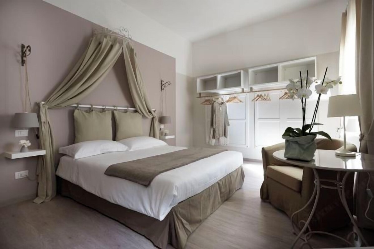 A bedroom with a bed, bedside tables, a chair, and a window with curtains.