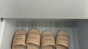 Ein Paar beige Farbschlappen mit dem Schriftzug 'XIXIAO' auf der Sohle, auf einer Holzfläche platziert.