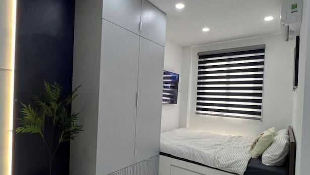 Ein modernes Schlafzimmer mit Bett, Einbauschrank und einem Fenster mit Jalousien.