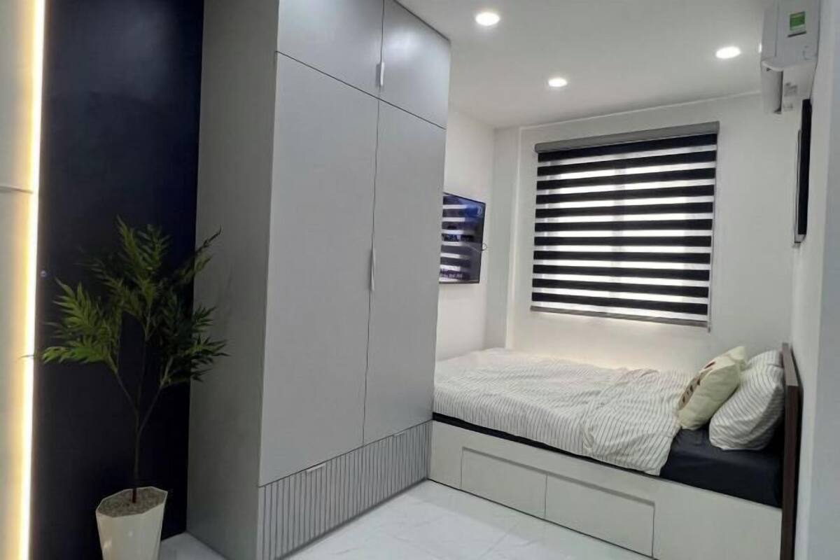 Ein modernes Schlafzimmer mit Bett, Einbauschrank und einem Fenster mit Jalousien.