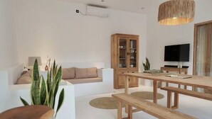 A modern living room with a wooden dining table, a sofa, and a cabinet. - Villa Enda (Bali)