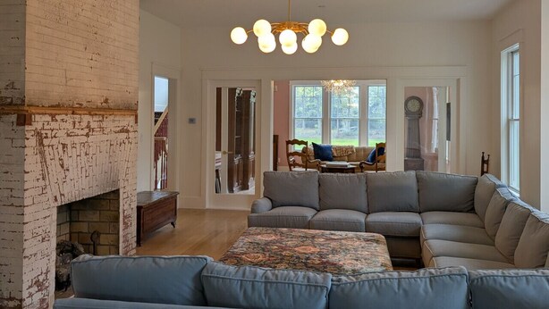 A living room with a fireplace, a sectional sofa, and a chandelier.