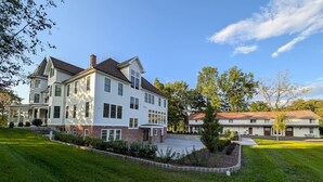 A large, multi-story building with a central courtyard, surrounded by well-maintained lawns and trees.