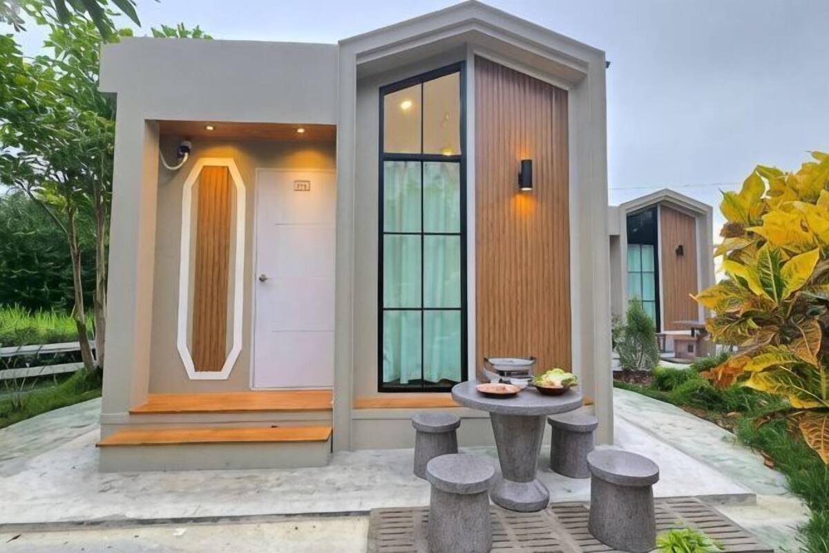 A modern building with a large door, a small table with dishes, and a garden area.