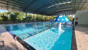 Uma piscina com decoração de cogumelo azul e branco, teto coberto e chão em mosaico.