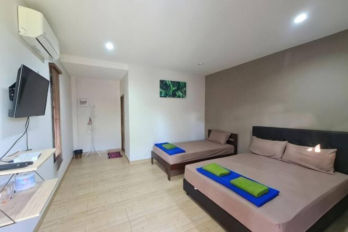 A hotel room with two beds, a TV, a desk, and a painting on the wall.