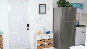 Eine Küche mit weißer Tür, einem Edelstahlkühlschrank und einem weißen Schrank.