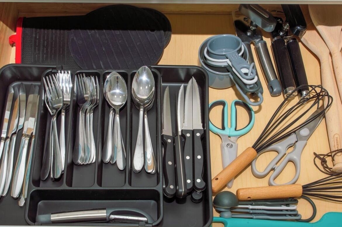 Un cassetto pieno di utensili da cucina, tra cui forchette, cucchiai, coltelli e una frusta.