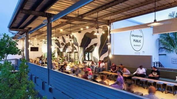 Ein Außenbereich des Grandview Public Market mit Tischen und Stühlen unter einem Vordach.