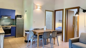 A compact kitchen with modern appliances, a dining area with a table and chairs, and a small seating area with a sofa. - Mini villa 5 (Propriano)