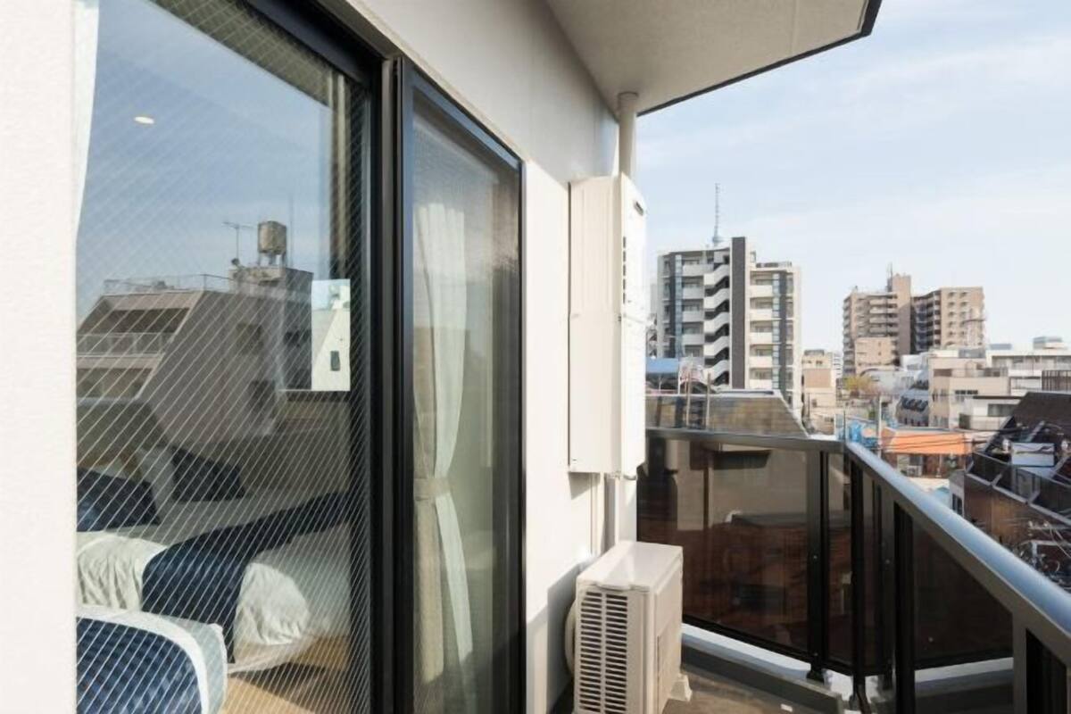 Un balcon avec vue sur la ville, une porte vitrée et un climatiseur blanc.