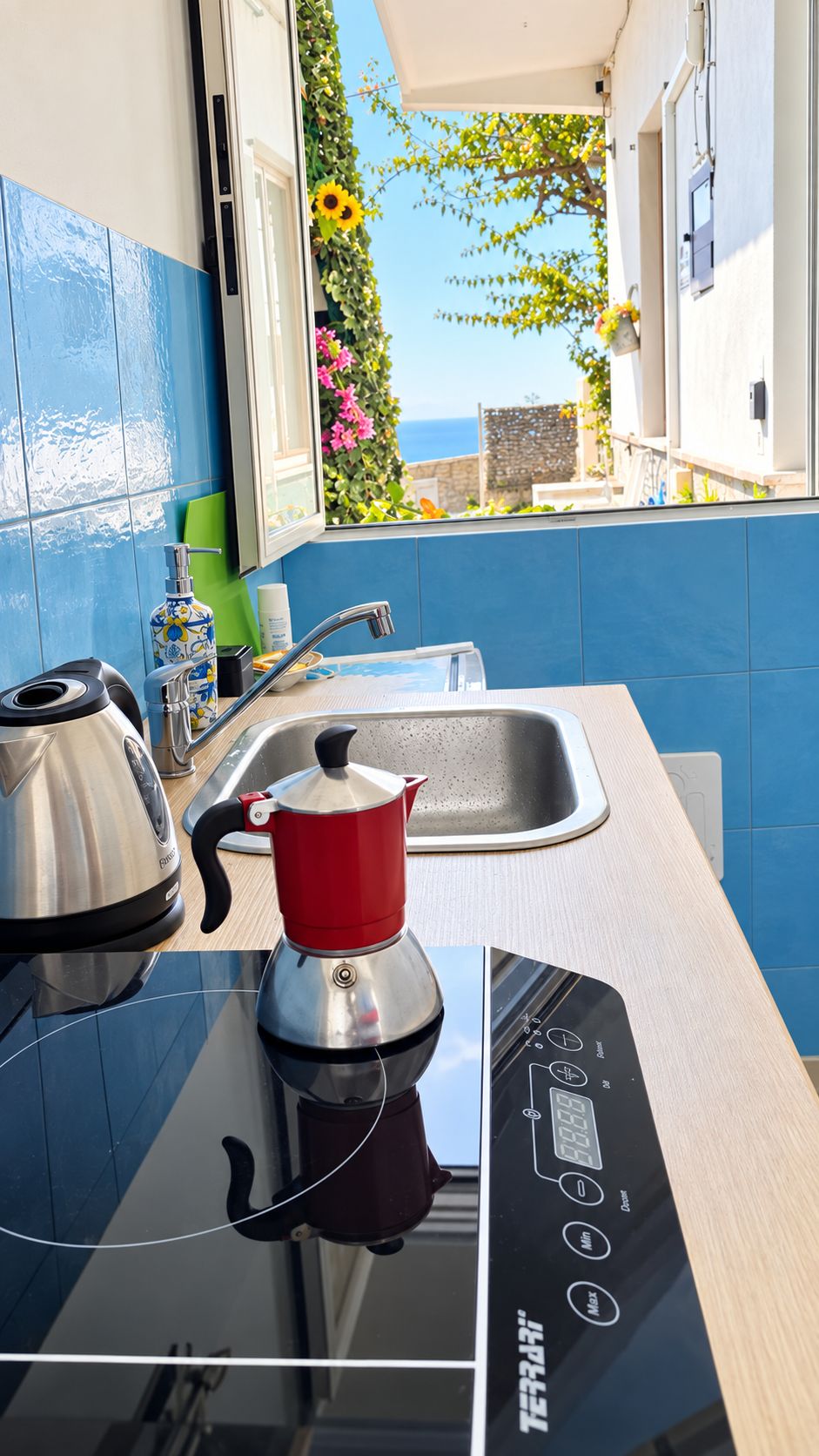Una cocina moderna con estufa integrada, hervidor y lavamanos.