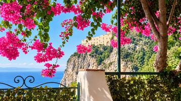 Une vue côtière avec un bâtiment perché sur une falaise, une balustrade et des fleurs roses.