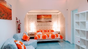 Une chambre à coucher avec un lit, deux tables de chevet, une étagère fixée au mur et un tableau.