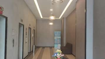 A hotel hallway with doors, a reception desk, and a signboard.