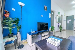 A modern living room with a flat-screen TV, a sofa, a coffee table, and potted plants. - #DP1, Cozy Park View Stay Above DPulze Mall (Cyberjaya)